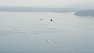 AX47_113E - 5K aerial stock footage of Kiowa Warrior helicopters flying over Elliott Bay, Seattle, Washington