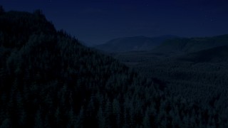 AX48_054_DFN - 4K day for night color corrected aerial stock footage of flying over wooded mountain slope toward a clear cut area, King County, Washington