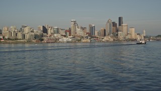 5K aerial stock footage of the Downtown Seattle skyline seen while flying low over Elliott Bay past a tugboat, Washington Aerial Stock Footage | AX49_089E