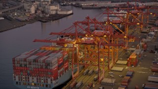 AX50_067 - 5K aerial stock footage of passing Harbor Island to approach a fully-laden cargo ship docked at the Port of Seattle, Washington, sunset