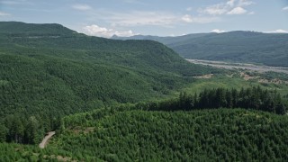 AX52_030 - 5K aerial stock footage fly over evergreen forest and hills to approach North Fork Toutle River in Washington