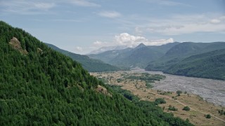 5K aerial stock footage pass a wooded slope to reveal North Fork Toutle River leading to Mount St. Helens, Washington Aerial Stock Footage | AX52_031E