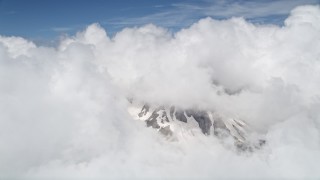 5K aerial stock footage of snowy slopes of Mount St. Helens peeking through cloud coverage, Washington Aerial Stock Footage | AX52_057