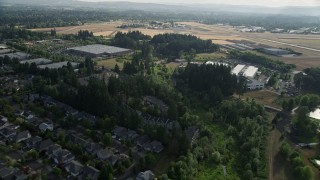 AX53_107E - 5K aerial stock footage fly over trees and fields approaching parked aircraft at Hillsboro Airport, Oregon