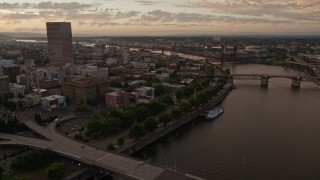 5K aerial stock footage follow the Willamette River toward the White Stag Sign in Downtown Portland, Oregon, sunset Aerial Stock Footage | AX54_106E