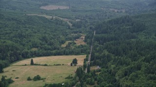 5K aerial stock footage of country road between farms and evergreen trees in Clatsop County, Oregon Aerial Stock Footage | AX56_038