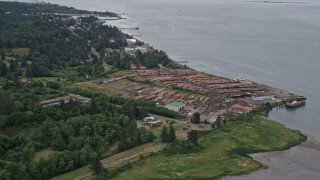 AX56_075E - 5K aerial stock footage of piles of lumber at a lumber yard beside the Columbia River in Warrenton, Oregon