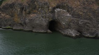 5K aerial stock footage track a cave at the base of a cliff, Cape Disappointment, Washington Aerial Stock Footage | AX56_101