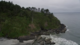 AX56_109E - 5K aerial stock footage fly over green cliff, revealing North Head Light, Ilwaco, Washington