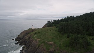 AX56_112 - 5K aerial stock footage of flying away from North Head Light on a coastal cliff, Ilwaco, Washington