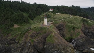 AX56_115E - 5K aerial stock footage orbit North Head Light on a cliff overlooking the Pacific Ocean, Ilwaco, Washington