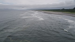 AX56_120E - 5K aerial stock footage of low altitude flight over ocean waves near an empty beach in Ilwaco, Washington