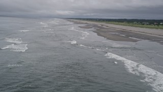 5K aerial stock footage fly over waves crashing into a beach around a lone beachgoer in Seaview, Washington Aerial Stock Footage | AX56_130E