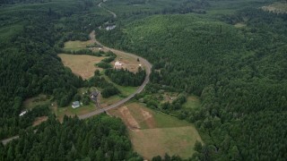 AX57_027 - 5K aerial stock footage of farms beside a country road and evergreen forest in Mason County, Washington