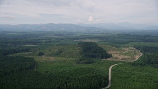 AX57_030 - 5K aerial stock footage of a winding road through logging areas and evergreen forest in Mason County, Washington