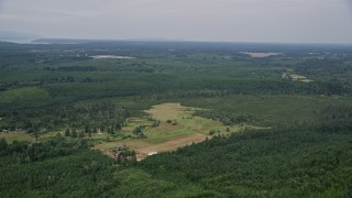 AX57_033 - 5K aerial stock footage fly over a hilltop logging area to approach a small farm, Shelton, Washington