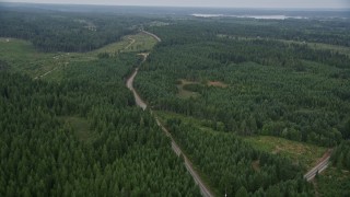 AX58_015E - 5K aerial stock footage fly over evergreen forest beside a road and logging area in Grapeview, Washington