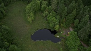 AX58_044 - 5K aerial stock footage tilt to bird's eye view of a small pond beside evergreen trees in Gig Harbor, Washington