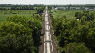 AX60_060 - 5K aerial stock footage follow railroad tracks to approach and fly over a train in Vacherie, Louisiana