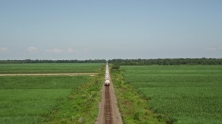 AX60_061 - 5K aerial stock footage of following railroad tracks to chase a train passing sugar cane fields, Vacherie, Louisiana