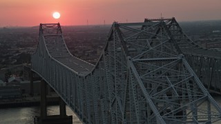 AX61_070 - 5K aerial stock footage of light traffic on the Crescent City Connection Bridge and setting sun in the background, New Orleans, Louisiana