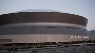 AX61_079 - 5K aerial stock footage of a slow descent and landing by the Superdome at sunset, Downtown New Orleans, Louisiana