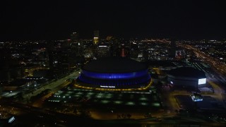 AX62_006E - 5K aerial stock footage fly over the Superdome at night and approach skyscrapers in Downtown New Orleans, Louisiana