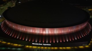 5K aerial stock footage of Mercedes-Benz Superdome with orange lighting at night, Downtown New Orleans, Louisiana Aerial Stock Footage | AX63_023E