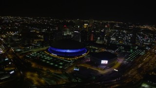 AX63_026 - 5K aerial stock footage orbit Superdome and New Orleans Arena to reveal Downtown New Orleans skyscrapers at night, Louisiana