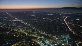 AX64_0285E - 5K aerial stock footage of Venice Boulevard between car dealerships and apartment buildings in Palms, Los Angeles, California, twilight