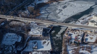 AX66_0026E - 4.8K aerial stock footage of Northern Boulevard Bridge over frozen river in snow covered area, Roslyn, New York