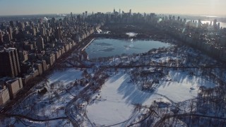 AX66_0196E - 4.8K aerial stock footage of Central Park in snow, tilt to reveal Midtown Manhattan, New York City