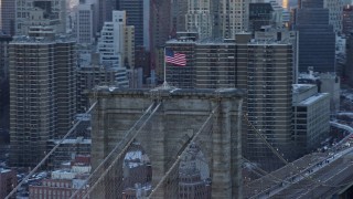 AX66_0235 - 4.8K aerial stock footage orbit flag on top of the Brooklyn Bridge, New York City, at sunset