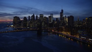 AX66_0398E - 4.8K aerial stock footage of Manhattan and Brooklyn Bridges, approaching Lower Manhattan skyline, New York City, twilight