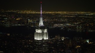 AX67_0046 - 4.8K aerial stock footage view of the Empire State Building with Hudson River in the background at night, Midtown Manhattan, New York City, New York