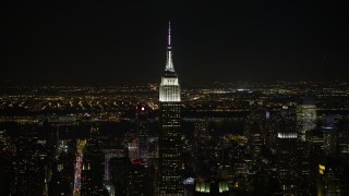 4.8K aerial stock footage view of orbiting the Empire State Building, Jersey City in the distance at night, Midtown Manhattan, New York City, New York Aerial Stock Footage | AX67_0047