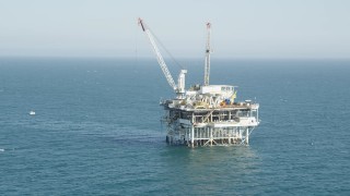 AX68_089 - 4.8K aerial stock footage of orbit of an oceanic oil platform near Long Beach, California