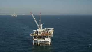 4.8K aerial stock footage orbit of an oceanic oil platform with Long Beach in the background, California Aerial Stock Footage | AX68_097