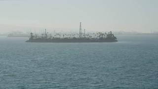 AX68_125 - 4.8K aerial stock footage tilt from San Pedro Bay to reveal Island Chaffee oil island, Long Beach, California