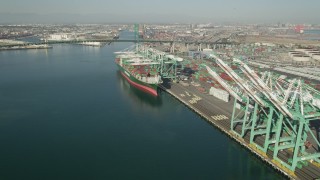 AX68_162 - 4.8K aerial stock footage approach a cargo ship beneath cranes at Port of Los Angeles, California