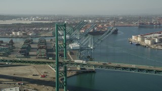 AX68_164 - 4.8K aerial stock footage fly over Vincent Thomas Bridge to approach cranes at the Port of Los Angeles, California