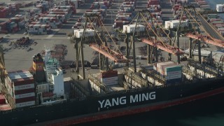 AX68_168 - 4.8K aerial stock footage of cranes working over a cargo ship at the Port of Los Angeles, California