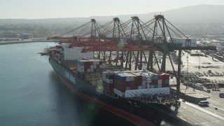 AX68_169 - 4.8K aerial stock footage orbit cranes unloading a cargo ship at the Port of Los Angeles, California