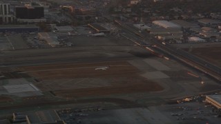 AX69_004 - 4.8K aerial stock footage of tracking an airliner landing on a runway at LAX Airport at sunset, California