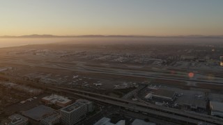 AX69_005 - 4.8K aerial stock footage of sunset at LAX with an airliner on a runway in Los Angeles, California