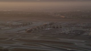 AX69_006 - 4.8K aerial stock footage of terminals, hangars and airliners at LAX at sunset, Los Angeles, California