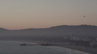 AX69_027 - 4.8K aerial stock footage tilt from helicopter to reveal Santa Monica Pier at sunset, California