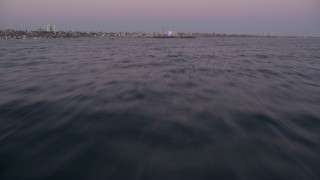 4.8K aerial stock footage fly low over the ocean and tilt to reveal Santa Monica Pier at twilight, California Aerial Stock Footage | AX69_045