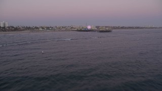 AX69_046 - 4.8K aerial stock footage tilt from the ocean to reveal and approach Santa Monica Pier at twilight, California