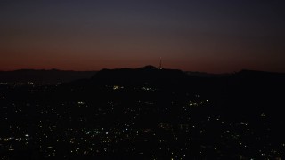 AX69_135 - 4.8K aerial stock footage of radio tower and the lights of homes atop the Hollywood Hills at night, California